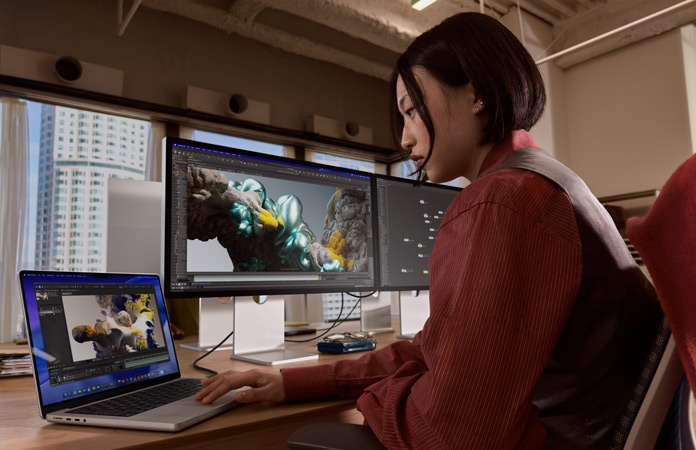 Pessoa a trabalhar num escritório com o MacBook Pro ligado a um Studio Display XDR