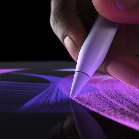 Un Apple Pencil Pro, vue latérale, blanc, main tenant un crayon et traçant une ligne d’un bleu vif avec le pinceau