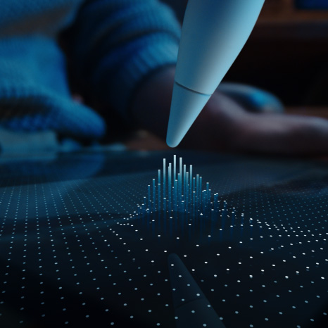Un Apple Pencil Pro, blanc, la pointe du crayon survole l’écran d’un iPad affichant une grille de points dont certains se transforment en colonnes en suivant la pointe de l’Apple Pencil Pro