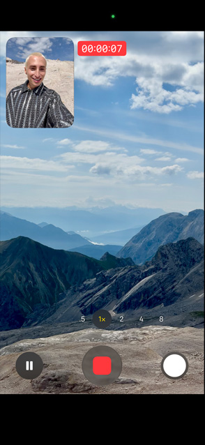 Une personne fait la démonstration d’une vidéo double capture en s’enregistrant avec la caméra avant tout en filmant le paysage montagneux avec la caméra arrière